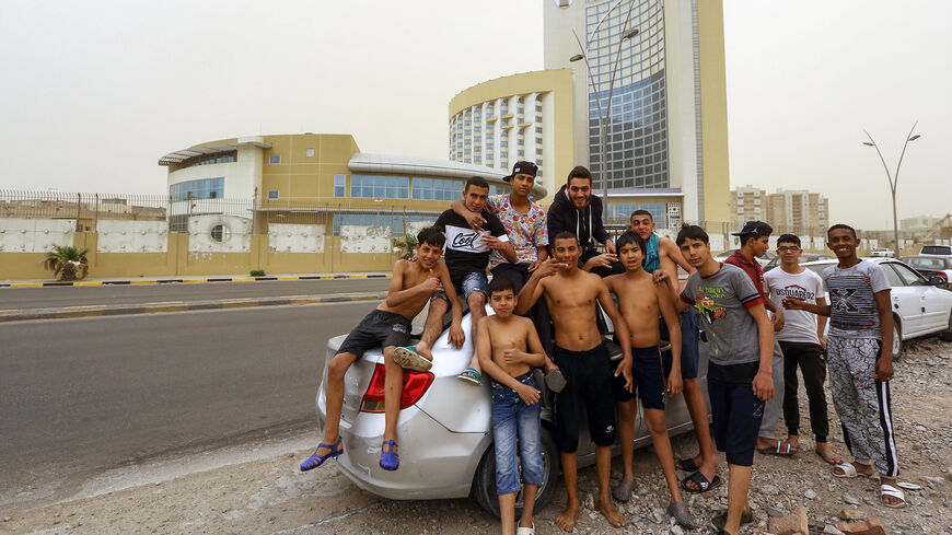 Libyan youths pose for a picture in front of the Corinthia Hotel after a swim near the city's main port, Tripoli, Libya, April 22, 2019.