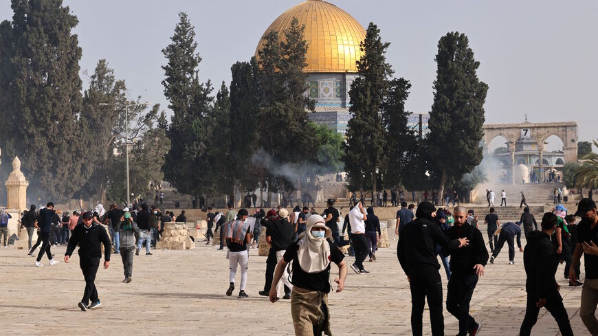 Palestinians run for cover from tear gas fired by Israeli security forces at Jerusalem's Al-Aqsa mosque compound on May 10, 2021, ahead of a planned march to commemorate Israel's takeover of Jerusalem in the 1967 Six-Day War. 