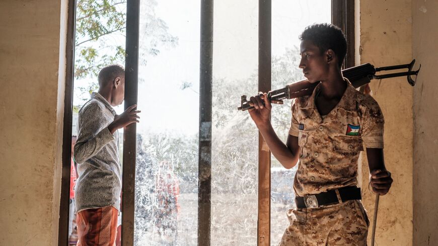 TOPSHOT - A man exits a door as a policeman stands next by at the compound of the Agda Hotel, in the city of Semera, Afar region, Ethiopia, on February 14, 2022. - Thousands of Eritrean refugees, shell-shocked and separated from loved ones, fled on foot through harsh terrain to escape artillery and gunfire. (Photo by EDUARDO SOTERAS / AFP) (Photo by EDUARDO SOTERAS/AFP via Getty Images)