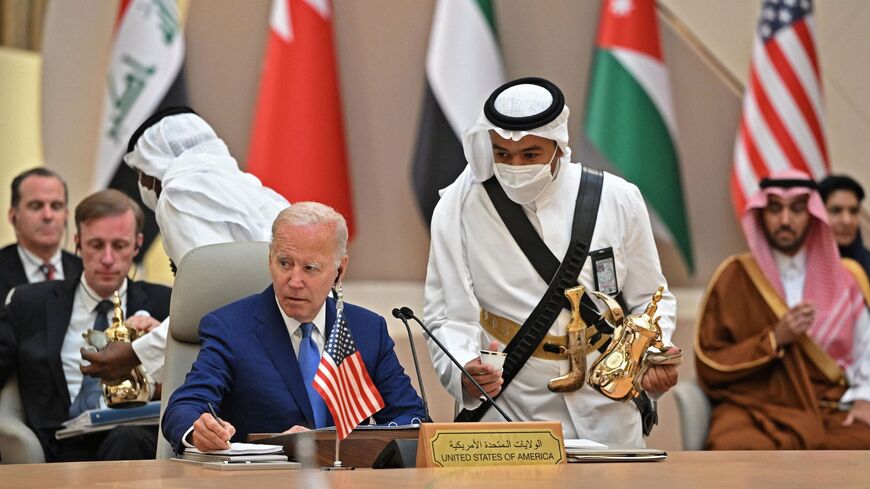 US President Joe Biden takes notes while an usher serves coffee during the Jeddah Security and Development Summit (GCC+3) at a hotel in Saudi Arabia's Red Sea coastal city of Jeddah on July 16, 2022. 