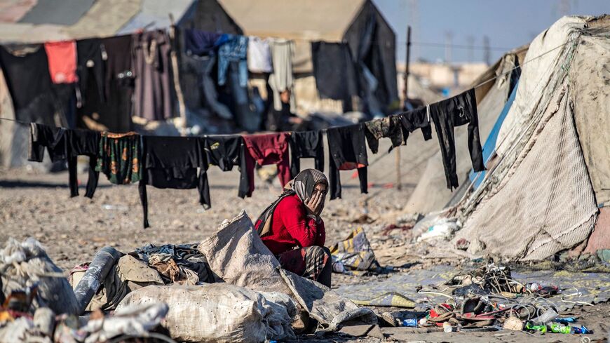 A woman sits outside a tent at a camp for those displaced by conflict in the countryside near Syria's northern city of Raqa on December 19, 2022. (Photo by Delil SOULEIMAN / AFP) (Photo by DELIL SOULEIMAN/AFP via Getty Images)