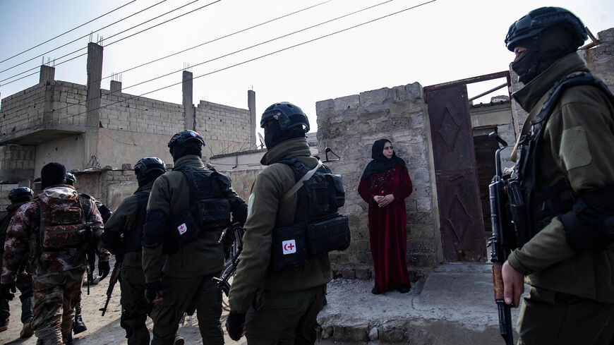 Syrian Kurdish Asayish security forces walk past a house during a raid against suspected Islamic State fighters in Raqqa, Syria, Jan. 29, 2023.