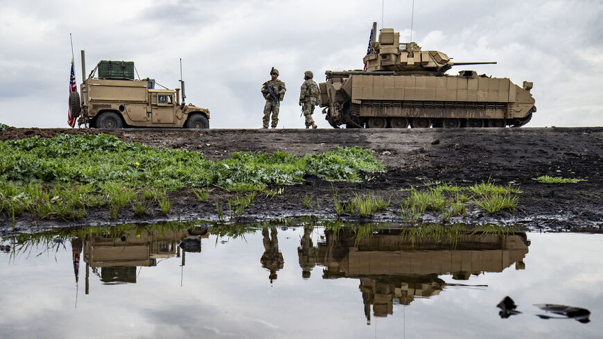 US army soldiers stand near armoured military vehicles on the outskirts of Rumaylan in Syria's northeastern Hasakeh province, bordering Turkey, on March 27, 2023. (Photo by Delil souleiman / AFP) (Photo by DELIL SOULEIMAN/AFP via Getty Images)