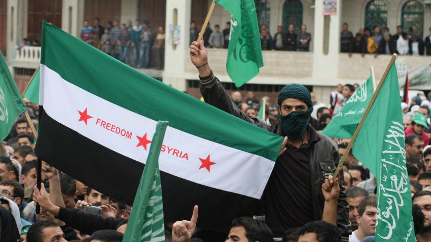 Palestinian supporters of the Islamist movement Hamas wave their flag and a pre-Baath Syrian flag (C) during a demonstration in the West Bank city of Hebron on November 21, 2012, against the ongoing Israeli military offensive on the Gaza Strip. Israel launched its offensive on November 14 with the targeted killing of a Hamas military chief. Since then, 147 Palestinians and five Israelis have been killed. AFP PHOTO/HAZEM BADER        (Photo credit should read HAZEM BADER/AFP via Getty Images)