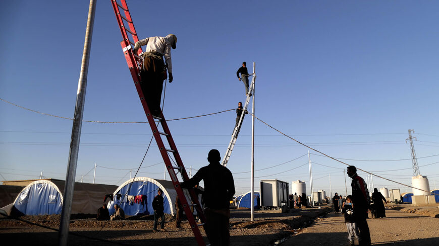Workers install electric wires for Iraqi refugees as they set up a new part of the Khazir refugee camp near the Kurdish checkpoint of Aski Kalak, 40 kilometers (25 miles) west of Erbil, Iraqi Kurdistan, Nov. 21, 2016.