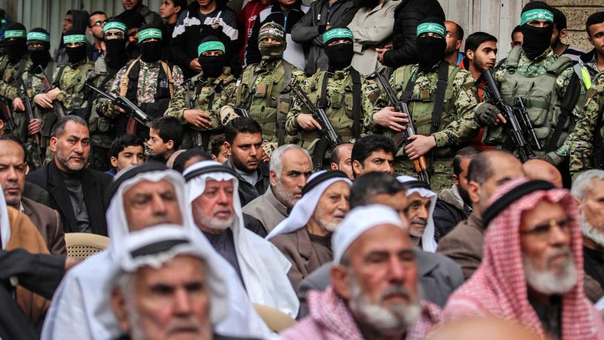 Palestinian men watch as fighters from the Ezzedine al-Qassam Brigades, the armed wing of the Palestinian Hamas movement, take part in a military show ahead of the 30th anniversary of the movement's founding in the southern Gaza Strip city of Khan Yunis on December 5, 2017. / AFP PHOTO / SAID KHATIB        (Photo credit should read SAID KHATIB/AFP/Getty Images)