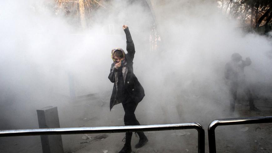 TOPSHOT - An Iranian woman raises her fist amid the smoke of tear gas at the University of Tehran during a protest driven by anger over economic problems, in the capital Tehran on December 30, 2017.
Students protested in a third day of demonstrations sparked by anger over Iran's economic problems, videos on social media showed, but were outnumbered by counter-demonstrators. / AFP PHOTO / STR        (Photo credit should read STR/AFP/Getty Images)