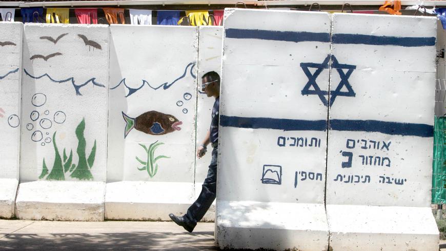 An Israeli settler walks between concrete walls for protection at the Jewish West Bank settlement of Ganim.   An Israeli settler walks between concrete walls for protection at the Jewish West Bank settlement of Ganim, May 24, 2005. Ganim and another three Jewish settlements, Kadim, Homesh and Sa-Nur, at the northern part of the West Bank are about to be removed as part of Israel's disengagement plan in Gaza and north Samaria. Photo taken May 24, 2005. REUTERS/Nir Elias - RP6DRNASSZAC