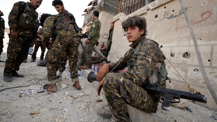 A fighter from Syrian Democratic Forces (SDF) sits on a curb as he holds his weapon in Raqqa, Syria September 25, 2017. REUTERS/Rodi Said - RC17FB8BC0B0