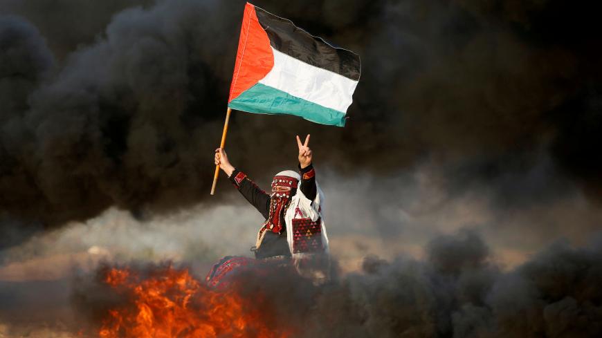 A woman waves a Palestinian flag during a protest calling for lifting the Israeli blockade on Gaza and demanding the right to return to their homeland, at the Israel-Gaza border fence east of Gaza City September 28, 2018. REUTERS/Mohammed Salem      TPX IMAGES OF THE DAY - RC18D059CEE0