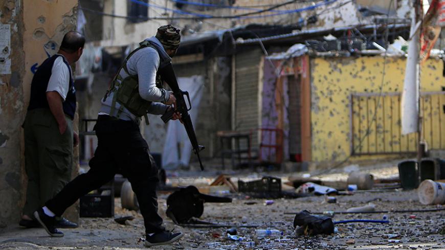 A Palestinian Fatah gunman carries his weapon and he attempts to cross a street at the Ain el-Hilweh refugee camp near Sidon, southern Lebanon April 10, 2017. REUTERS/Ali Hashisho     TPX IMAGES OF THE DAY - RTX34VZC