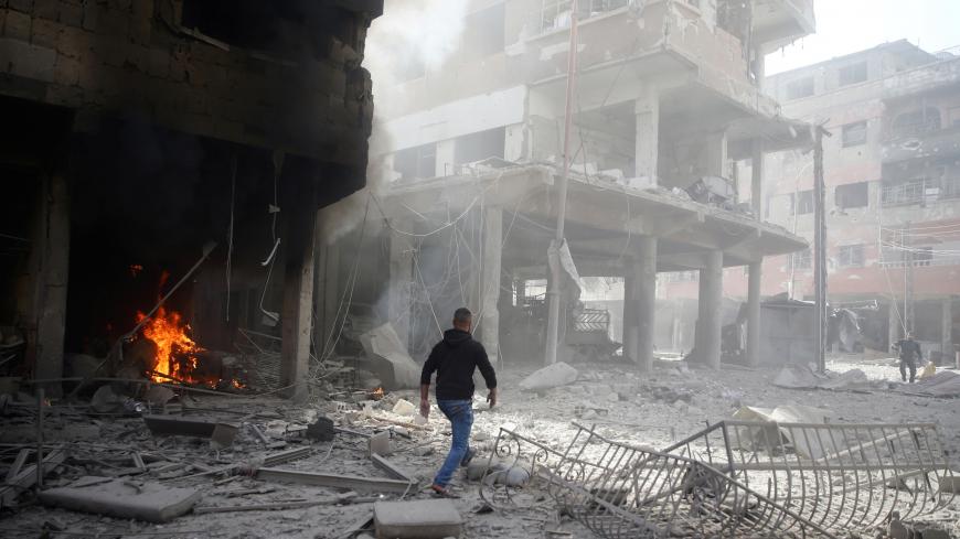 A man walks on rubble at a damaged site after an airstrike in the besieged town of Douma, Eastern Ghouta, Damascus, Syria February 9, 2018. REUTERS/Bassam Khabieh - RC18866F2CF0