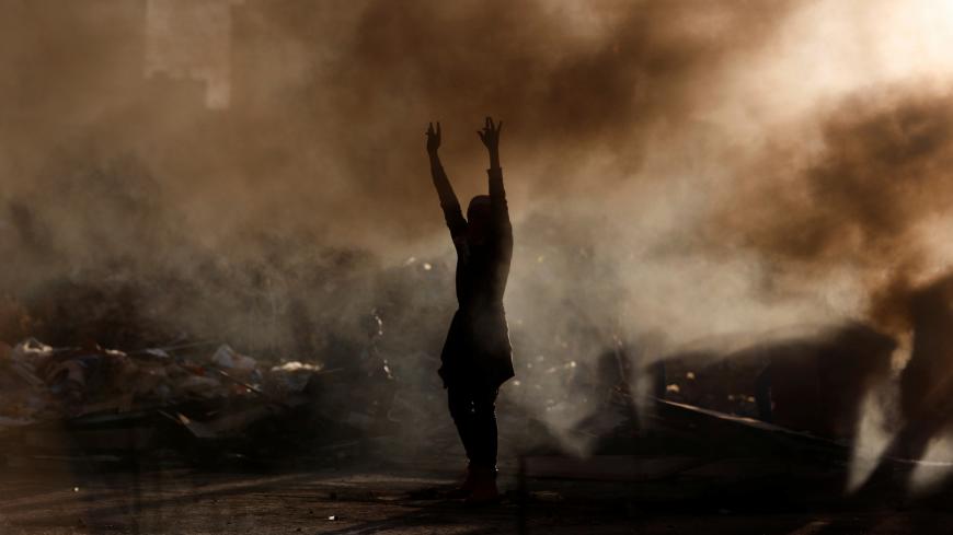 A Palestinian gestures as smoke rises during clashes with Israeli troops near the Jewish settlement of Beit El, near Ramallah, in the Israeli-occupied West Bank December 13, 2018. REUTERS/Mohamad Torokman - RC160B728C10